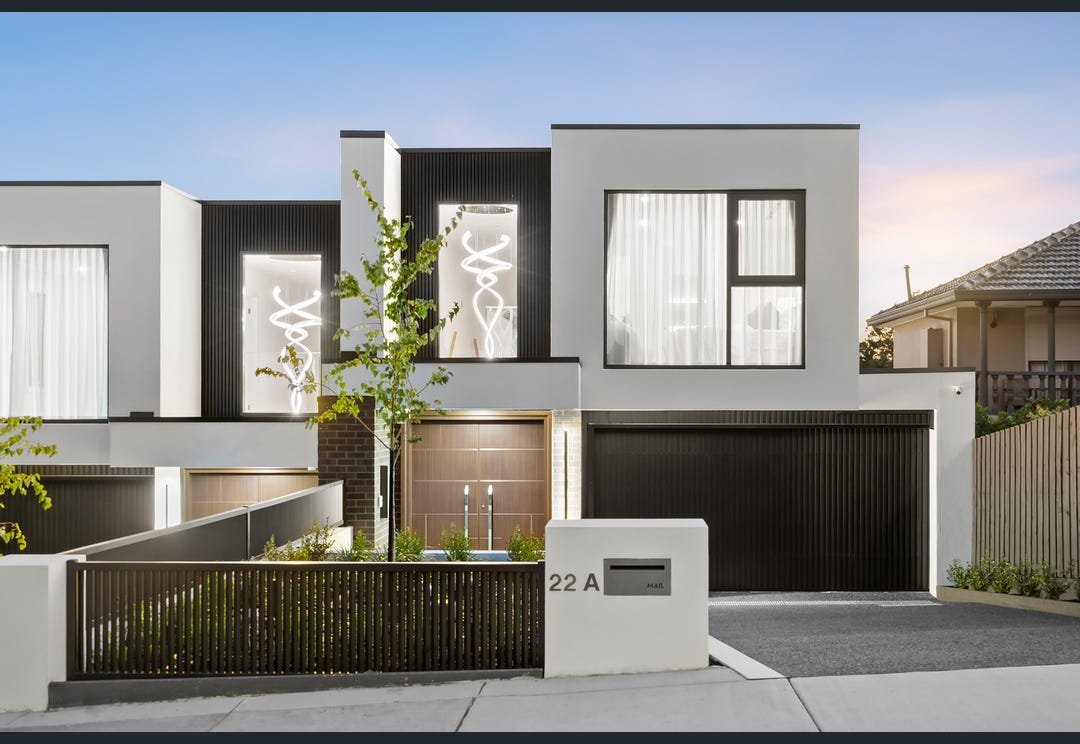 Modern two-storey home with a white facade, black cladding and a garage.