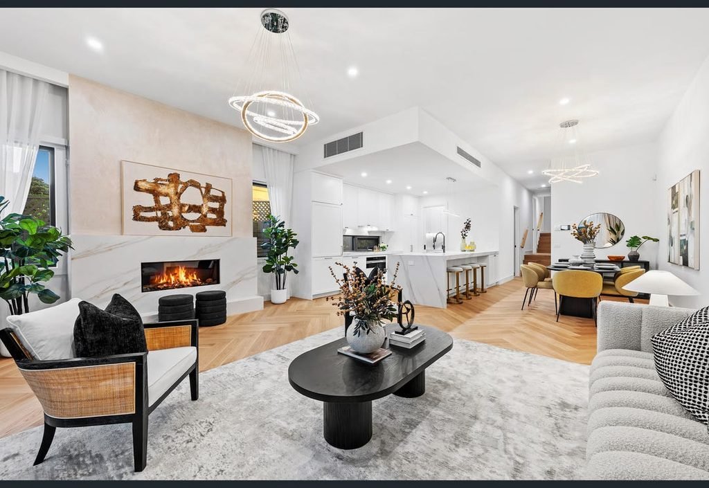 Open-plan living, kitchen and dining area with a fireplace and timber flooring.